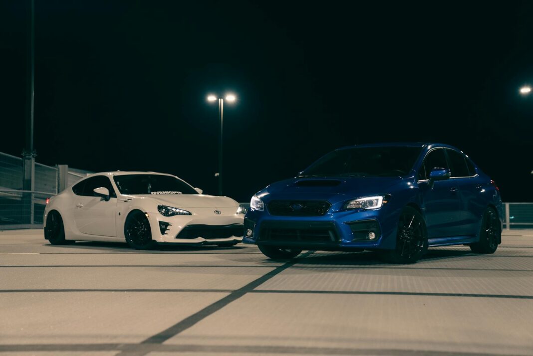 Biały i niebieski sportowy samochód zaparkowane nocą na dachu parkingu Biały i niebieski sportowy samochód zaparkowane nocą na dachu parkingu