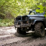 Czarny Nissan Patrol Y61 jedzie błotnistą leśną drogą