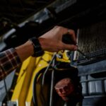 Mechanik z śrubokrętem sprawdza silnik używanego Subaru