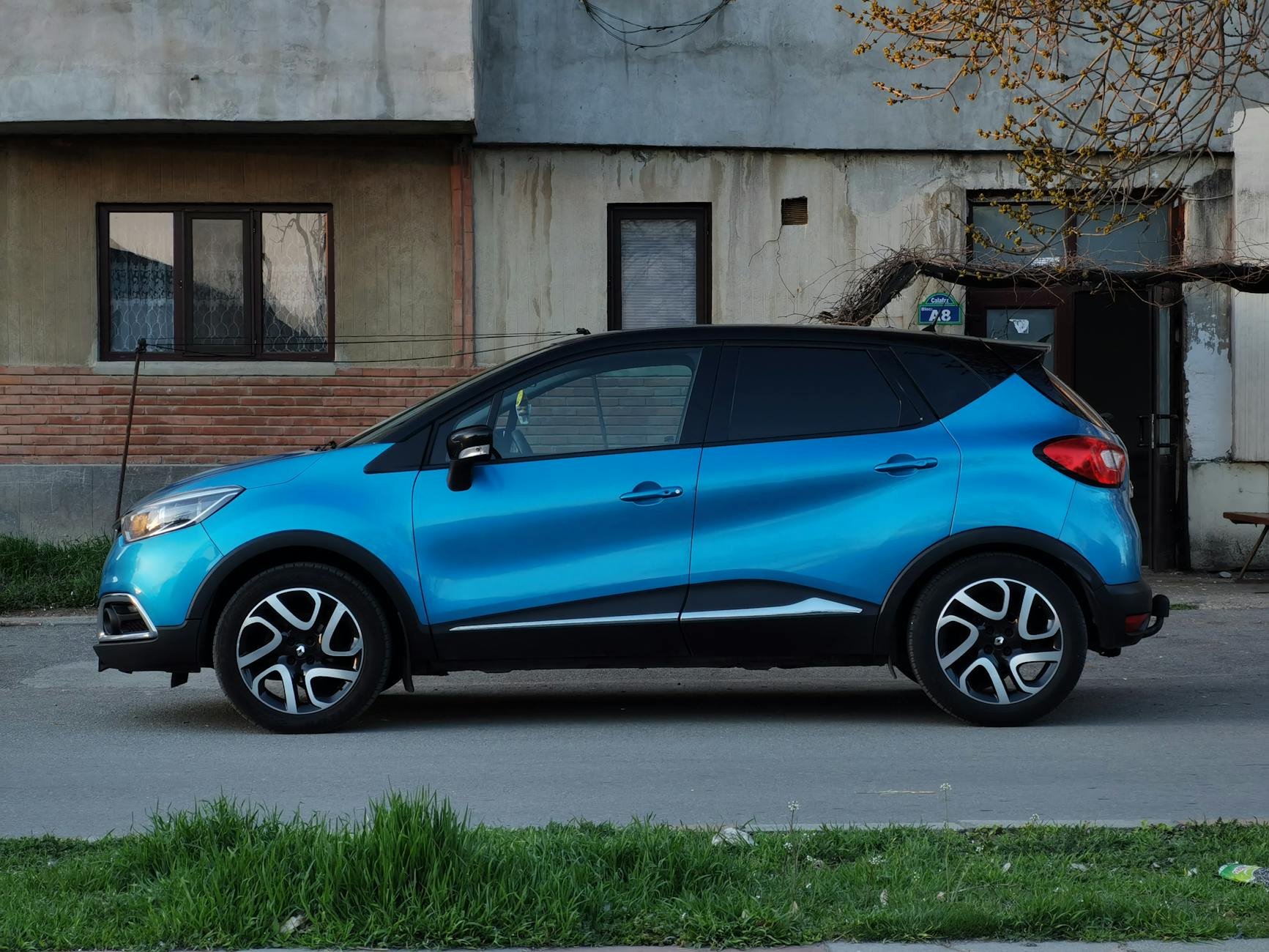 Niebieska Toyota C-HR zaparkowana przy ulicy obok starej kamienicy