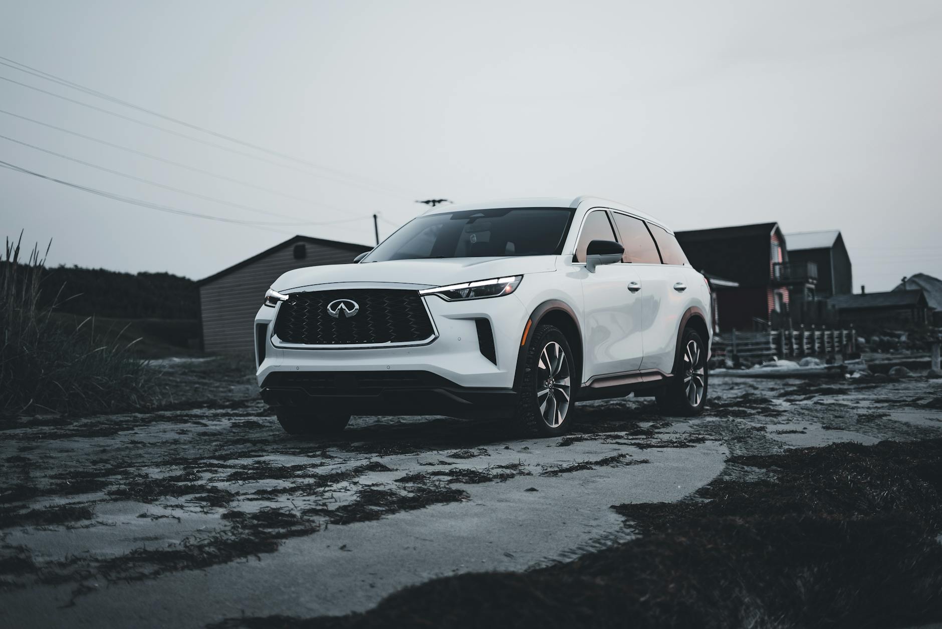 Białe Volvo SUV zaparkowane na wiejskiej drodze przy starych domach