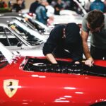 Czerwone Ferrari z mechanikami zaglądającymi pod maskę na zlocie klasyków