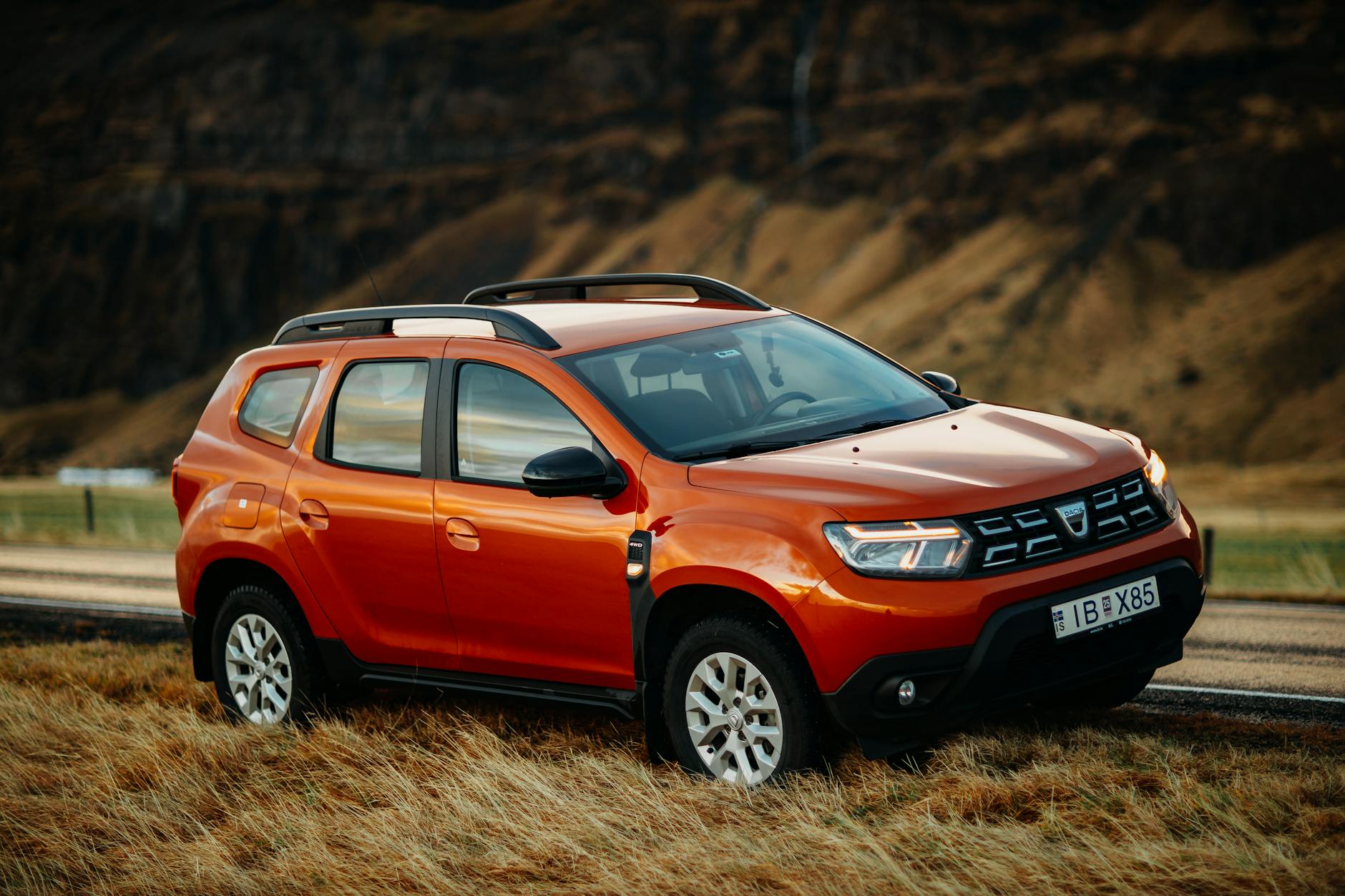 Czerwony Dacia Duster SUV zaparkowany przy wiejskiej drodze