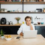 Kobieta pracuje na laptopie przy blacie nowoczesnej kuchni