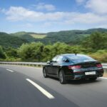 Cadillac ATS 2.0T: czy to niedoceniana alternatywa dla BMW serii 3? Czarny sedan sportowy jedzie krętą drogą w górskim, zielonym krajobrazie