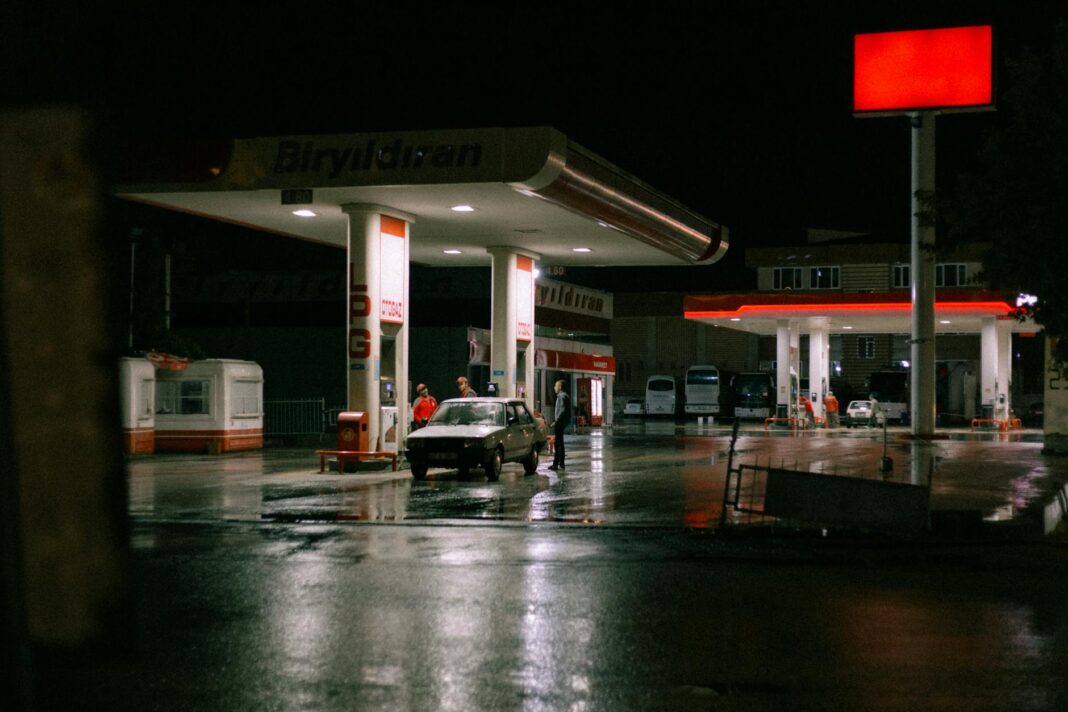 Samochód przy jasno oświetlonej stacji benzynowej nocą Samochód przy jasno oświetlonej stacji benzynowej nocą