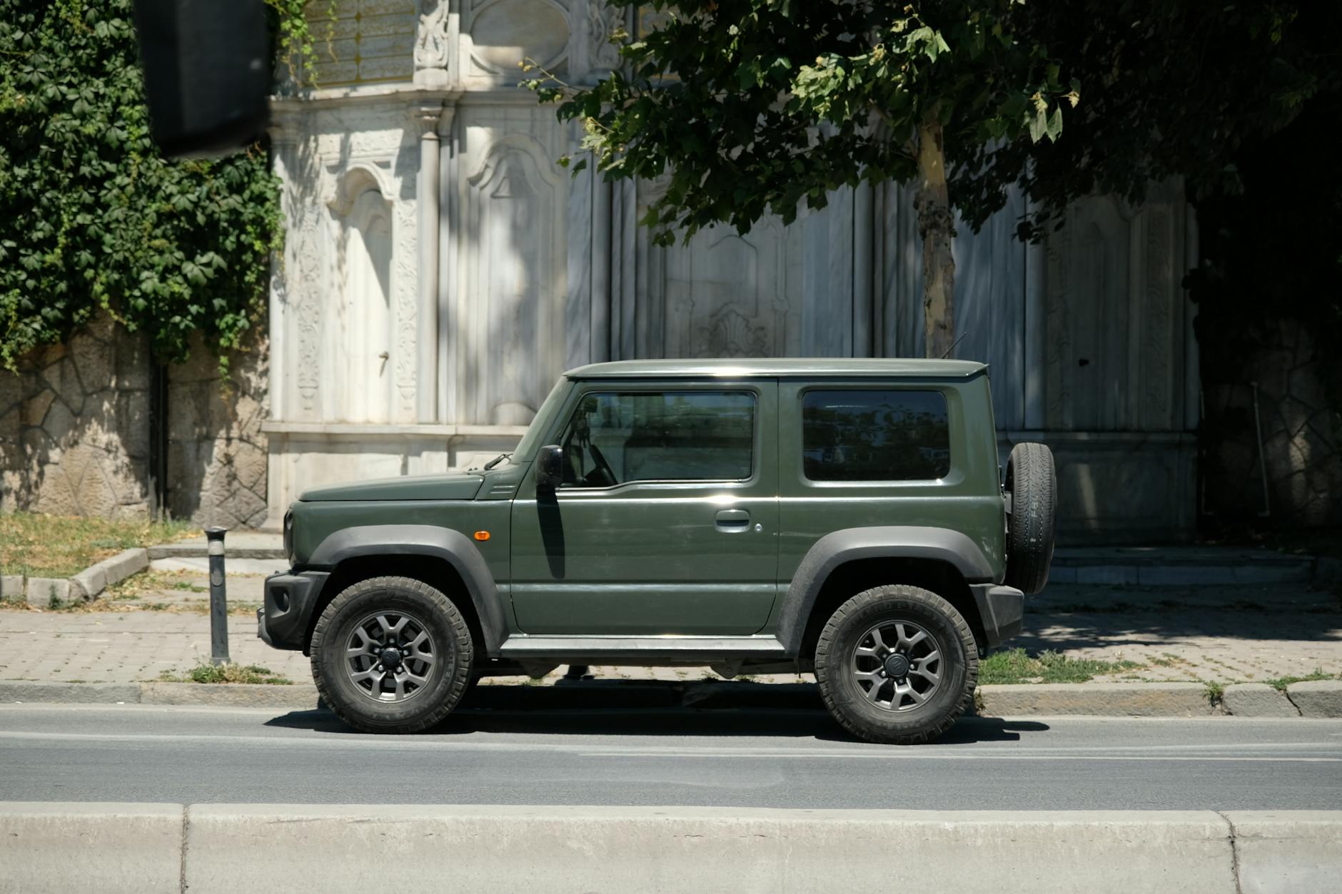 Zielony terenowy Suzuki 4x4 zaparkowany na słonecznej miejskiej ulicy