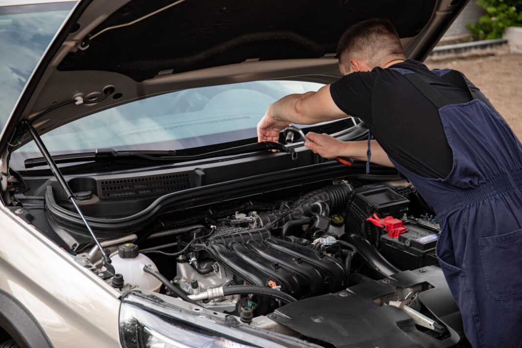 Mechanik naprawia silnik Citroëna C3 na zewnątrz w dzień Mechanik naprawia silnik Citroëna C3 na zewnątrz w dzień