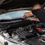 Citroën C3 używany: na co uważać przed zakupem? Mechanik naprawia silnik Citroëna C3 na zewnątrz w dzień