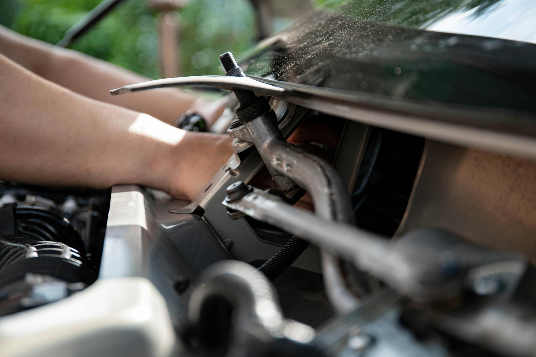 Mechanik naprawiający silnik Volkswagena, zbliżenie na dłonie i narzędzia