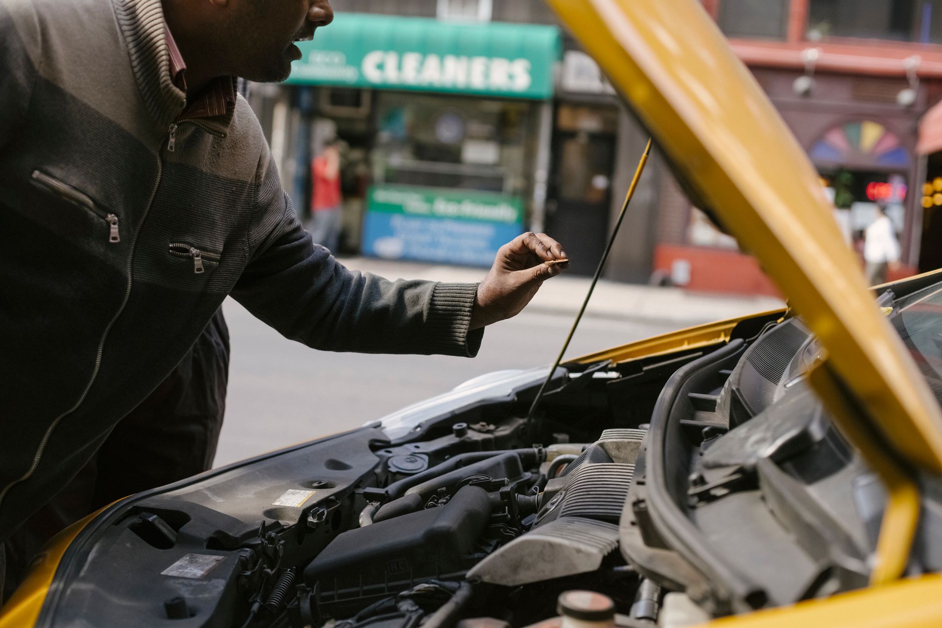 Mężczyzna naprawia silnik zepsutego Chevroleta zaparkowanego na ulicy