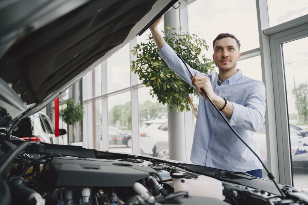 Mężczyzna sprawdza silnik Chevroleta w nowoczesnym salonie samochodowym Mężczyzna sprawdza silnik Chevroleta w nowoczesnym salonie samochodowym