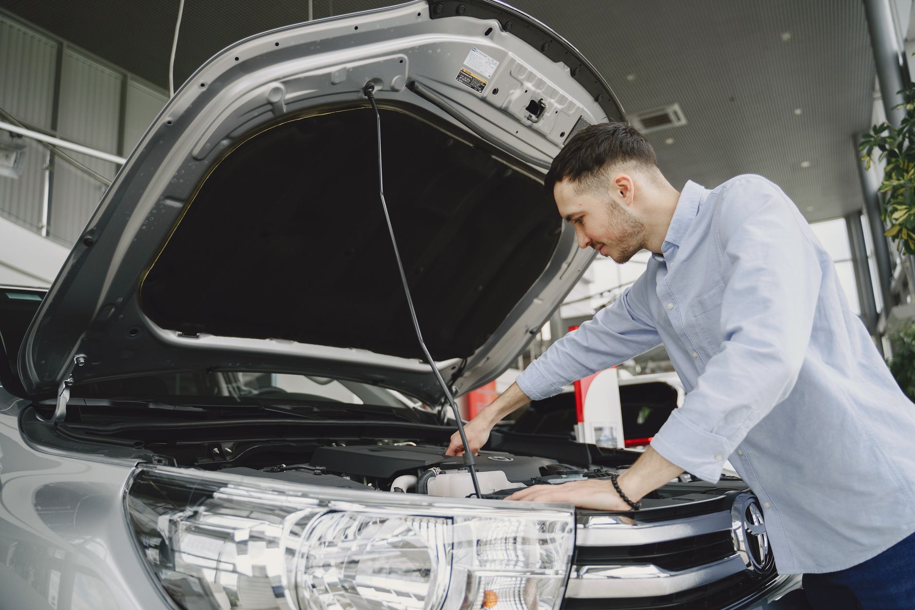 Mężczyzna w niebieskiej koszuli ogląda silnik auta w salonie Chevroleta