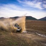Dacia Duster 4x4 w terenie: jak działa napęd i co warto doposażyć przed wyjazdem? Dacia Duster 4x4 jadąca w błocie w terenie offroad
