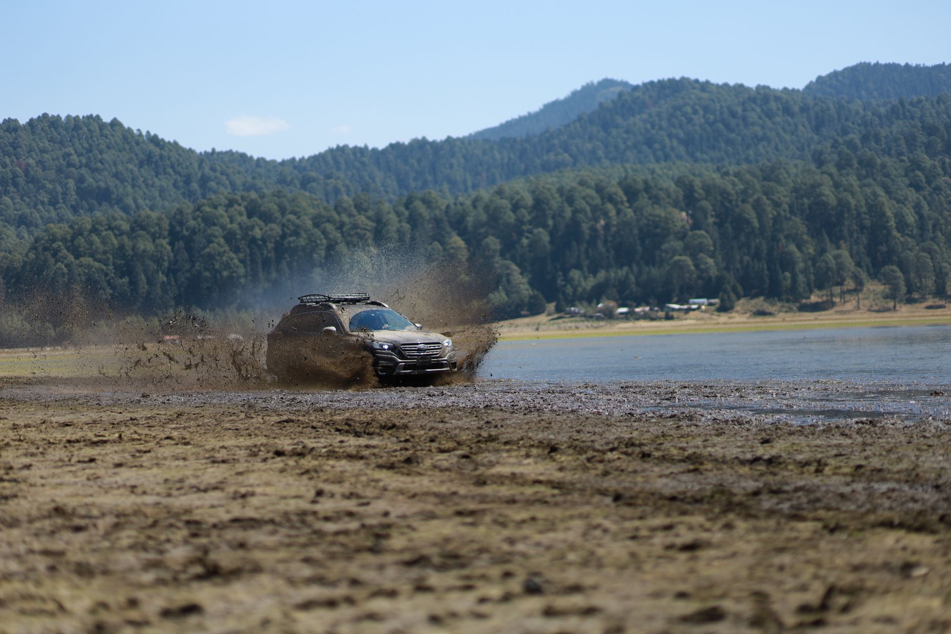 Dacia Duster 4x4 jedzie po błotnistej drodze w górach