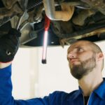 Mechanik serwisuje Forda Focusa pod podnośnikiem w warsztacie