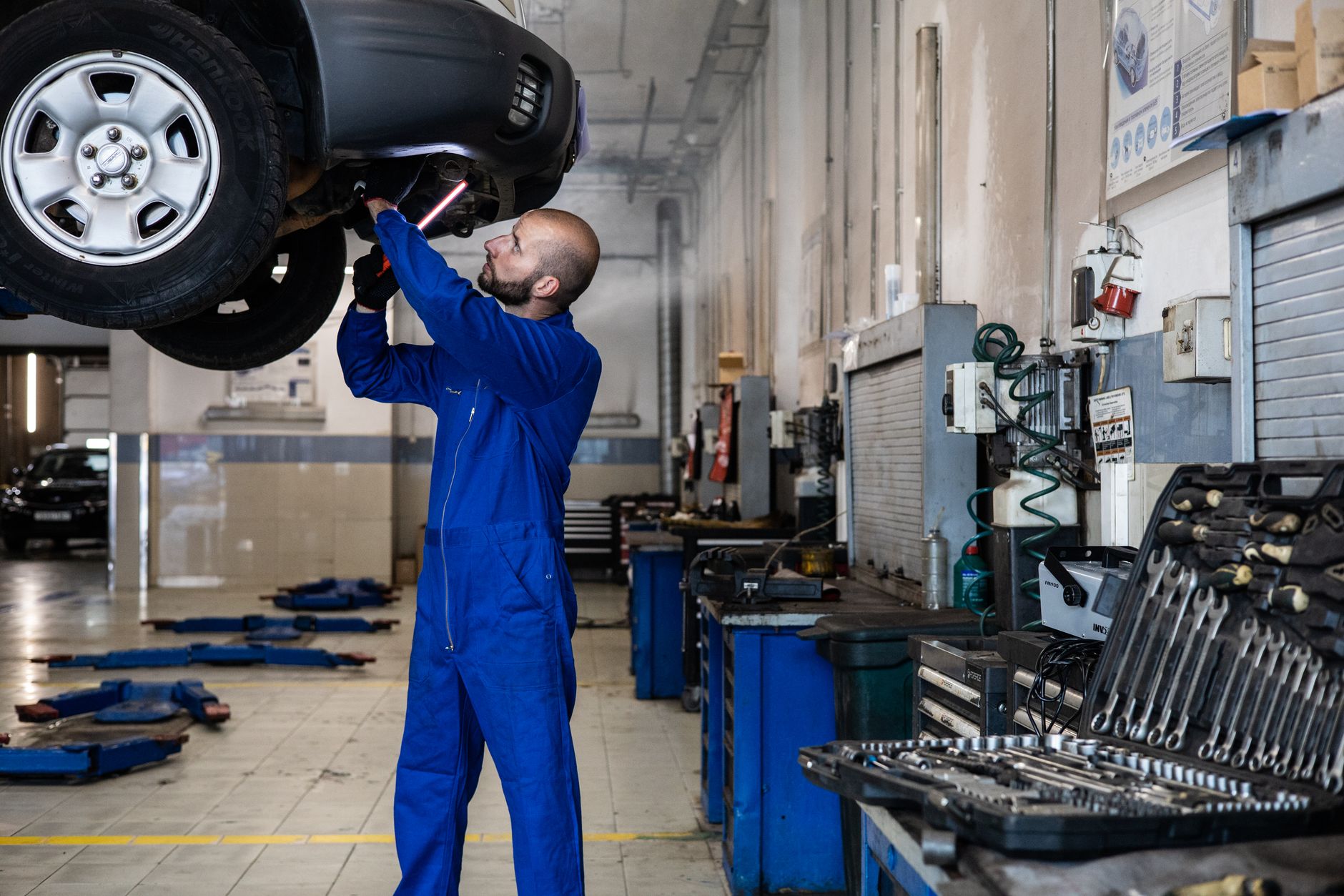 Mechanik sprawdza podniesiony Ford Focus w warsztacie samochodowym