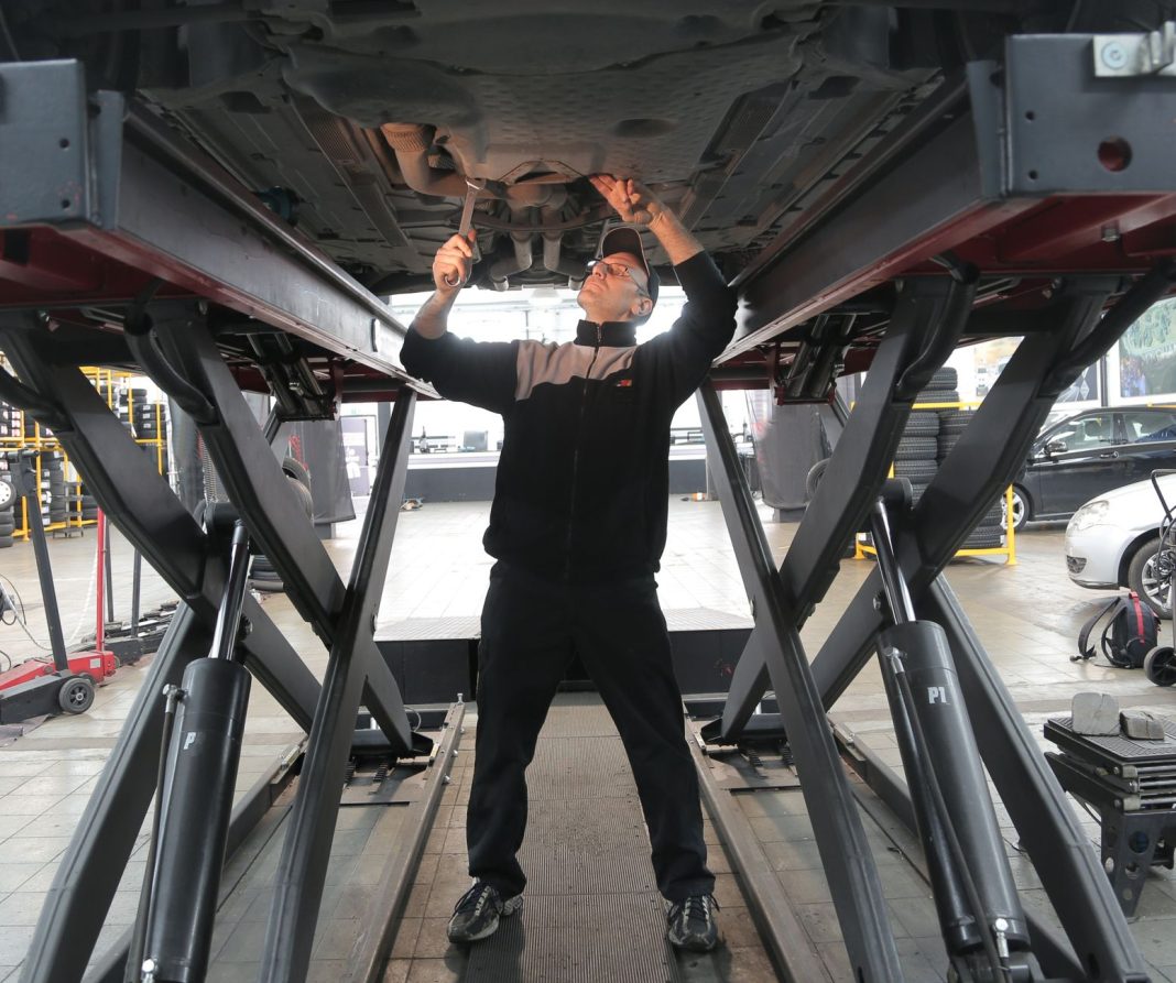 Mechanik sprawdza samochód w profesjonalnym warsztacie samochodowym Mechanik sprawdza samochód w profesjonalnym warsztacie samochodowym