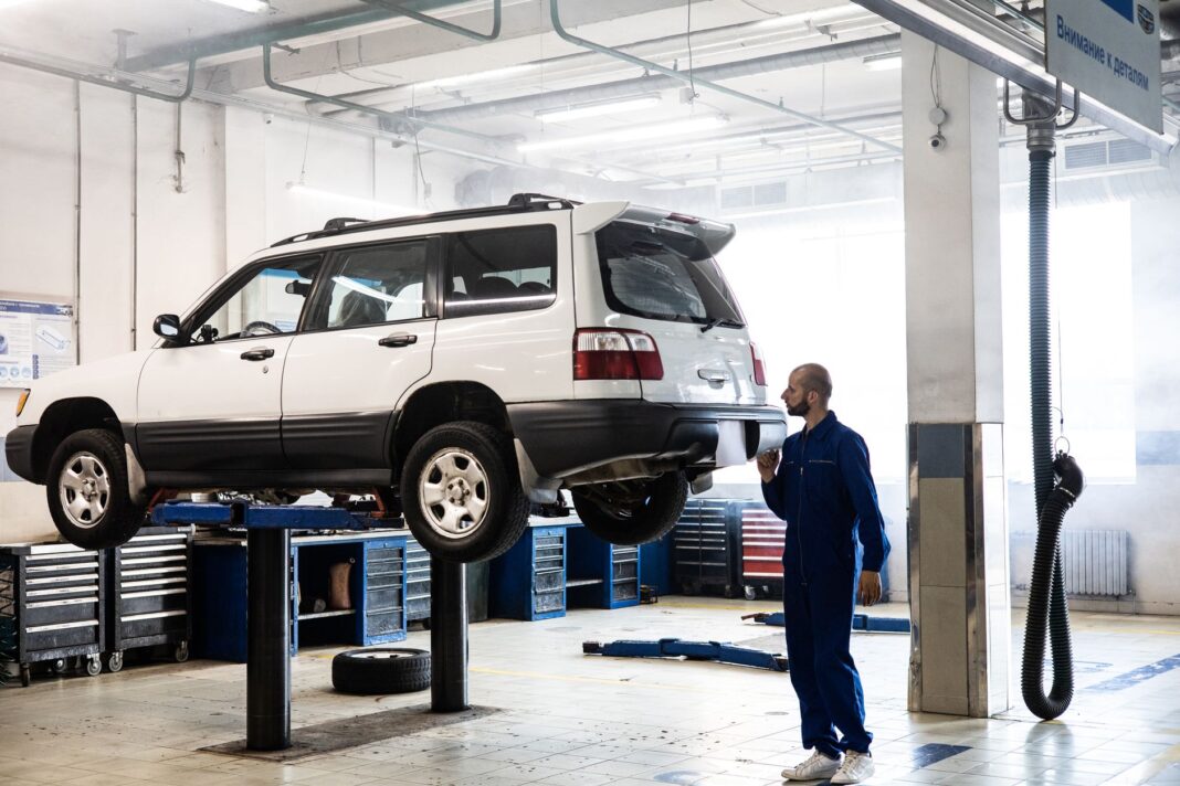 Mechanik sprawdza SUV na podnośniku w nowoczesnym warsztacie