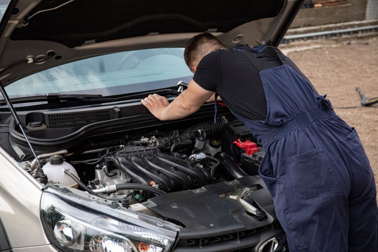 Mechanik sprawdzający silnik samochodu na zewnątrz